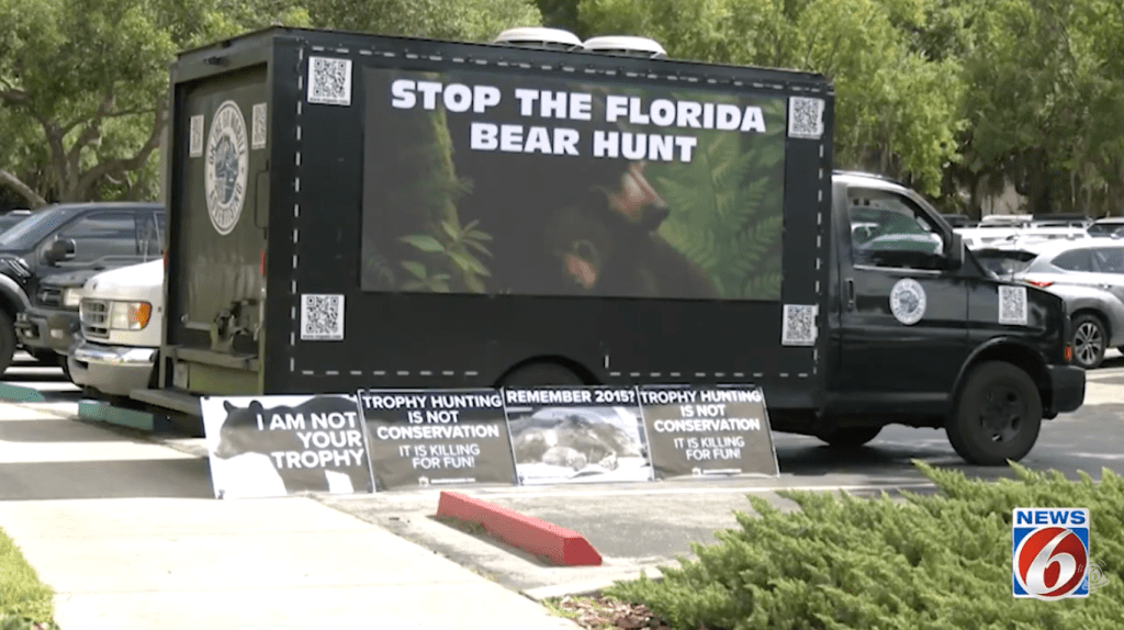 A protester sets up a van with a large sign calling for the end of the bear hunting permits in Florida.
